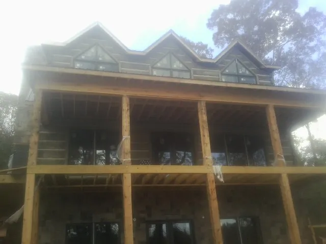 Dormers and porch framing on a large log home under construction — Roof Coating work by our crew in Iron Ridge