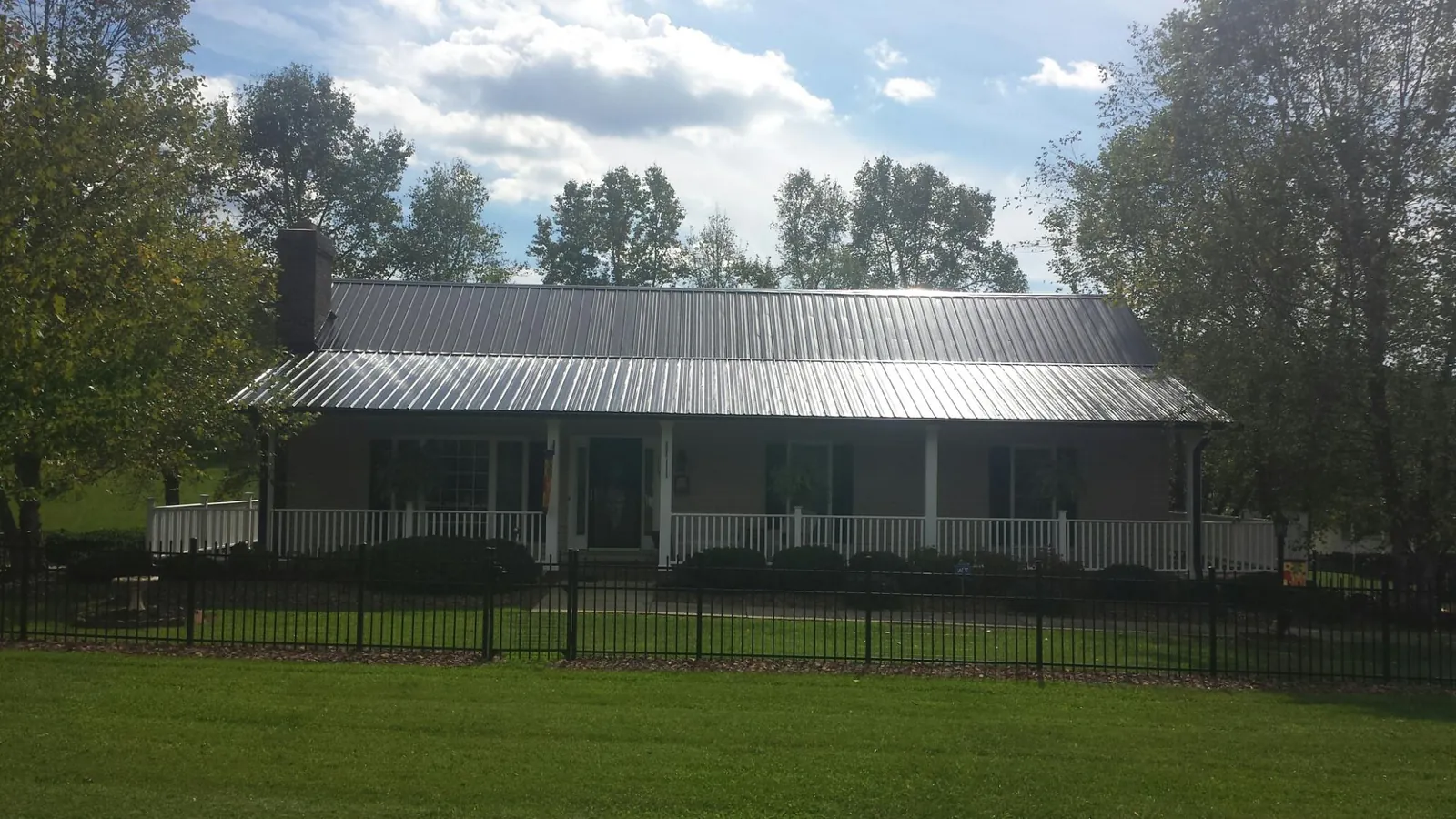 Gray metal roof on a brick ranch with a full width front porch — Gutter Guard Installation work by our crew in Iron Ridge