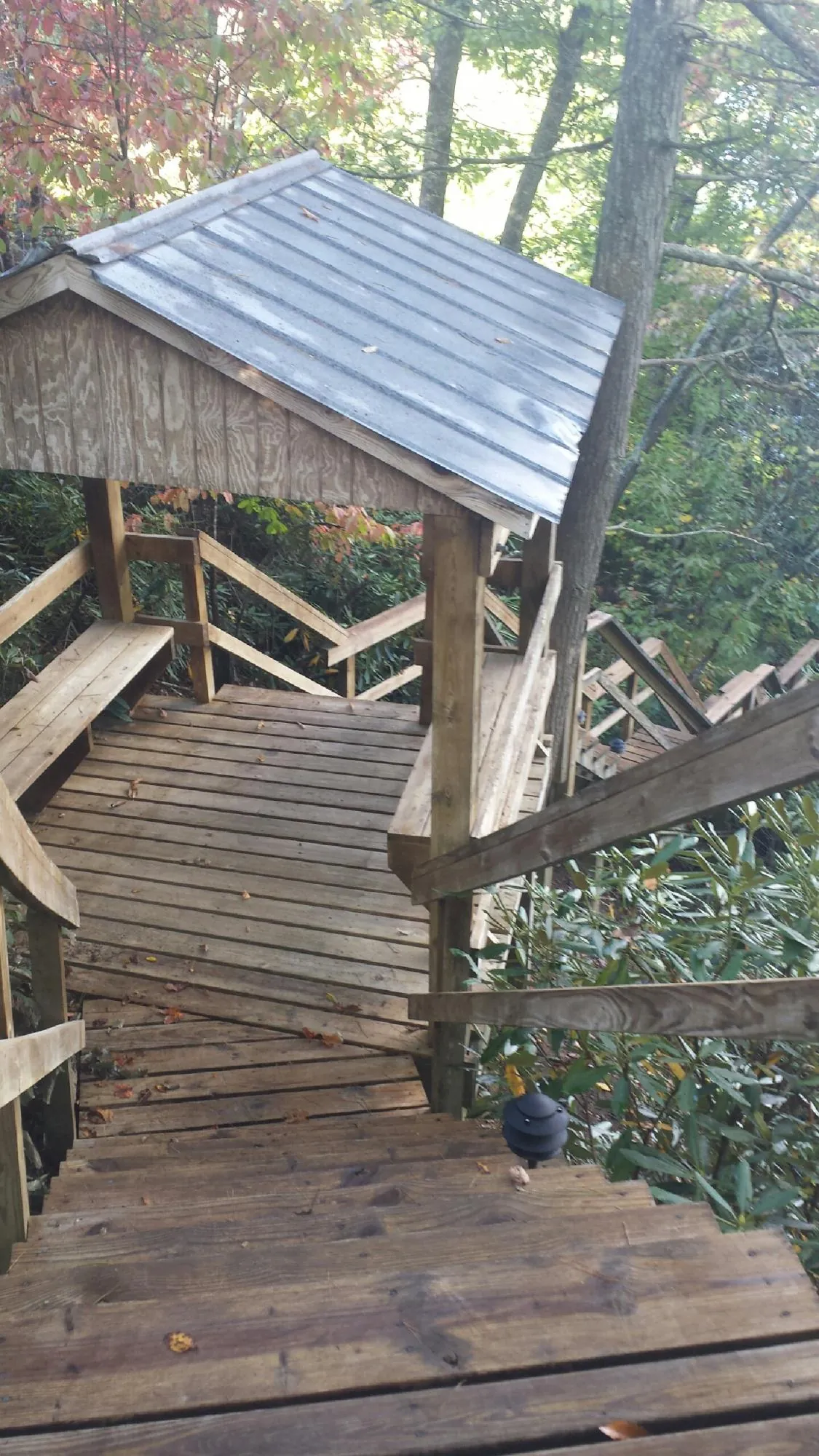Metal roofed shelter over wooden steps on a wooded walkway — Skylight Repair & Installation work by our crew in Iron Ridge