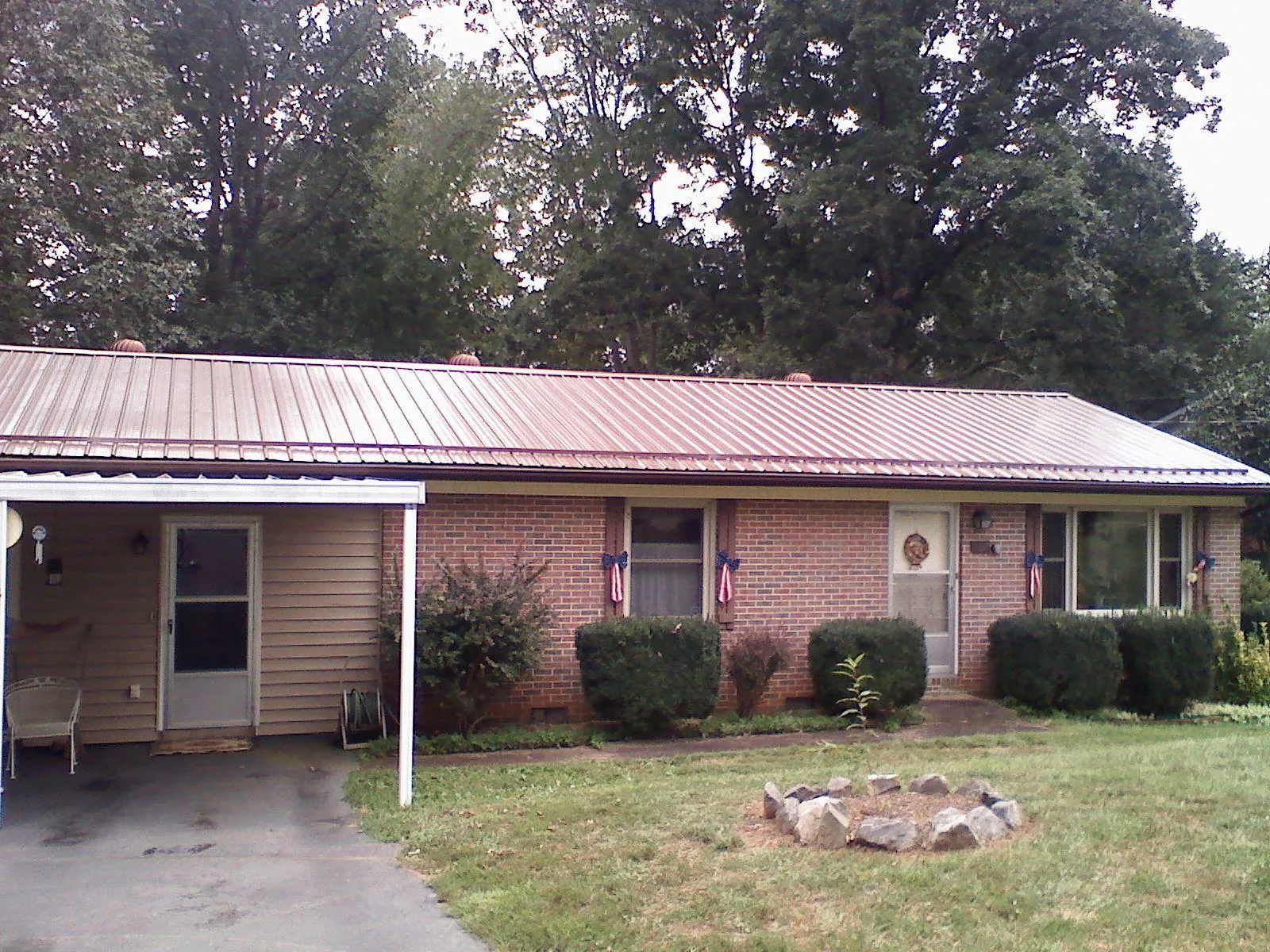 Bronze metal roof and carport on a brick ranch home — Roof Repair work by our crew in Iron Ridge
