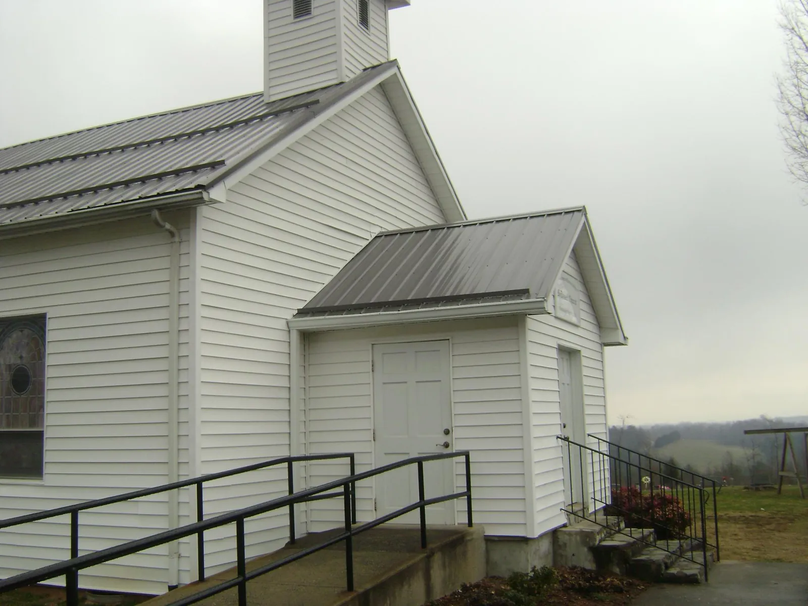 Gray metal roof on a white clapboard church with a steeple in Iron Ridge
