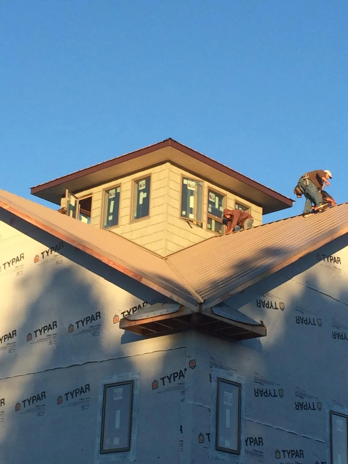 Roofers working around a rooftop cupola on a new metal roof at sunset — Roof Waterproofing in Iron Ridge by Roofing Brothers